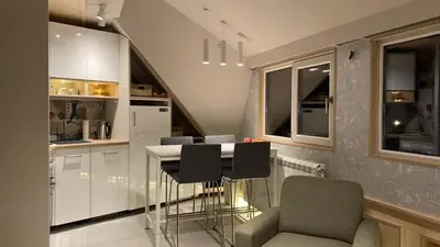 a kitchen with white cabinets and a table and chairs at Konaci Koznik Porodični in Kopaonik