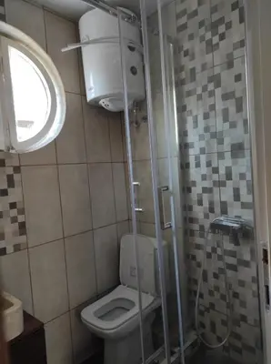 a small bathroom with a toilet and a shower at Dona Apartments 1 in Niš