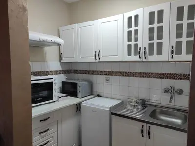 a white kitchen with white cabinets and a microwave at Dona Apartments 1 in Niš