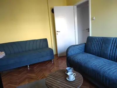 a living room with two blue couches and a table at Dona Apartments 2 in Niš