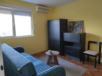 a living room with a blue couch and a table at Dona Apartments 2 in Niš