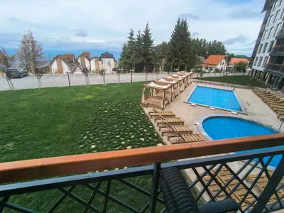 a balcony with a swimming pool and lounge chairs at Apartment 12 Kopaonik in Kopaonik