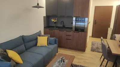 a living room with a blue couch and a kitchen at Apartment 12 Kopaonik in Kopaonik