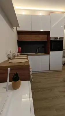 a kitchen with white cabinets and a black microwave at Apartman 