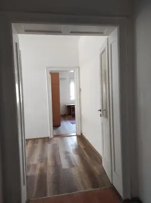 an empty hallway with white walls and wooden floors at Dona Rooms 3 in Niš