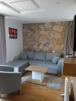 a living room with a couch and a stone wall at Vila Barselona Kopaonik in Raška