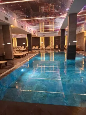 a swimming pool in a hotel with blue water at Waves Kopaonik, Residence Hill in Kopaonik