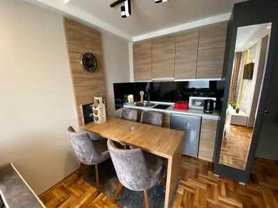 a kitchen with a wooden table and chairs at LaKop Apartman in Kopaonik