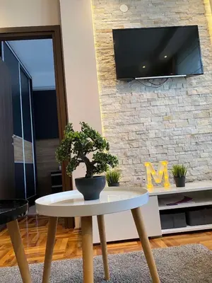 a living room with a table and a tv on a brick wall at LaKop Apartman in Kopaonik