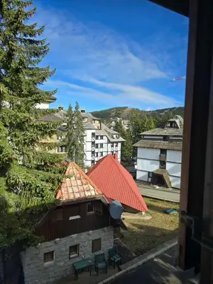 a building with an orange roof with benches and buildings at Apartman Leda in Kopaonik