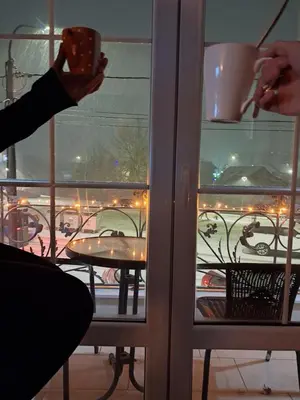 a person is holding a cup in front of a window at Dina lux apartman 2 in Jagodina