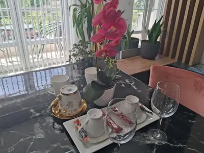 a table with glasses and a vase with red flowers at Dina lux apartman 2 in Jagodina