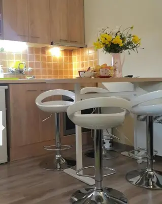 a kitchen with white bar stools and a counter at Mina in Kopaonik