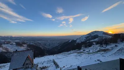a house on a snowy mountain with the sunset in the background at Vila Banovic in Kopaonik