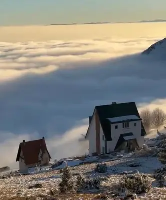 two houses on a mountain above a layer of clouds at Vila Banovic in Kopaonik