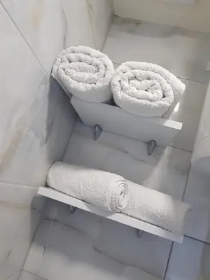 two rolls of towels on shelves in a bathroom at Sofy apartman in Niš