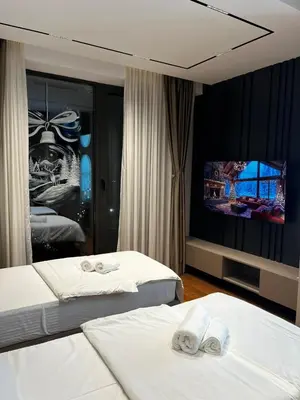 a hotel room with two beds and a flat screen tv at Planet Lux Apartment with secured parking In the garage in Niš