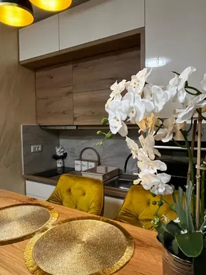 a dining room table with yellow chairs and white orchids at GOLDEN SS Studio in Vrnjačka Banja