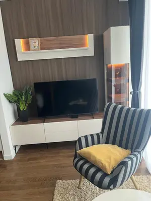 a living room with a tv and a striped chair at Delta SPA Residence in Niš
