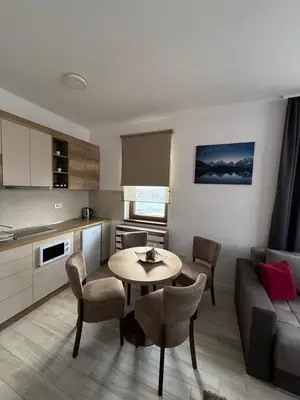 a kitchen and living room with a table and a couch at Vidik Residence A23 in Kopaonik