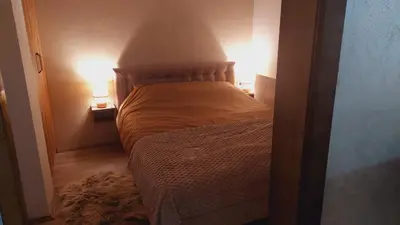 a bed in a small room with two lamps at Apartmani Marjanovic in Jagodina