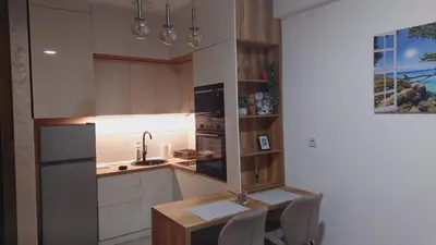 a kitchen with white cabinets and a table and chairs at Apartmani Marjanovic in Jagodina