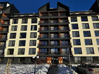 a large apartment building with snow in front of it at Woodland B65 Residence Hill Kopaonik in Kopaonik