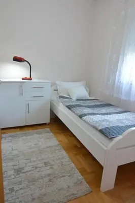 a bedroom with a bed and a dresser and a lamp at Apartman Nidža in Vrnjačka Banja