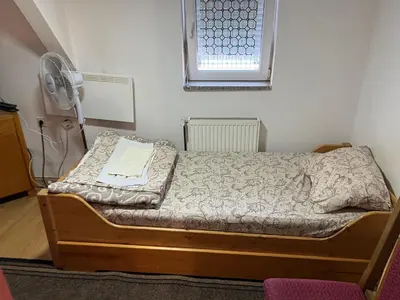 a small bedroom with a bed and a fan at Slobo Velickovic in Prokuplje