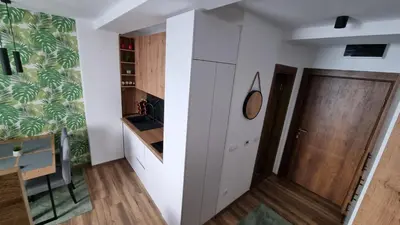 a small kitchen with white cabinets and a door at The View A74 in Raška