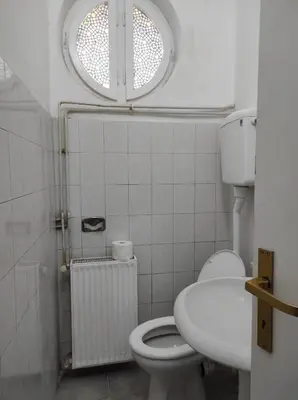 a bathroom with a toilet and a sink and a window at Dona Rooms 4 in Niš
