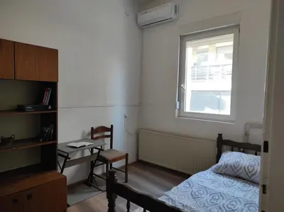 a bedroom with a bed and a desk and a window at Dona Rooms 5 in Niš