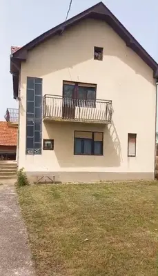 a white house with a balcony and a yard at Milutovac in Trstenik
