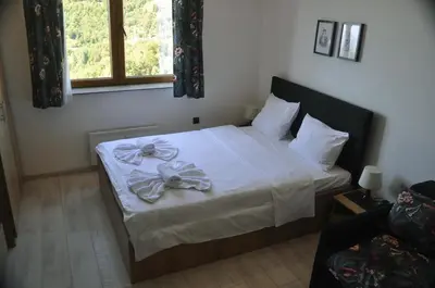 a bedroom with a bed with white sheets and a window at Milmari Apartman Kopaonik in Kopaonik