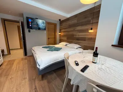 a bedroom with a bed and a table with a bottle of wine at Juli Kop in Kopaonik
