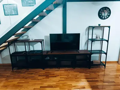 a living room with a tv and a staircase at M Central Park in Niš