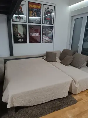 a large white bed in a room with posters on the wall at M Central Park in Niš