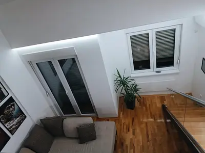 a living room with two windows and a couch at M Central Park in Niš