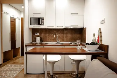 a kitchen with white cabinets and a wooden counter top at Apartment Spust in Kopaonik