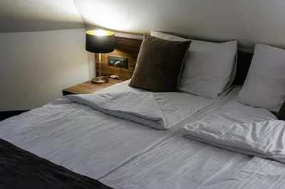 a large bed with white sheets and pillows at Apartman Spust Angella in Kopaonik