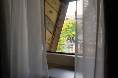 a window with a white curtain and a view at Apartman Spust Angella in Kopaonik