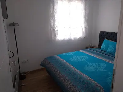 a bedroom with a bed with blue sheets and a window at Marta i Marija 2 in Vrnjačka Banja