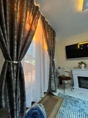 a living room with a large window with curtains at Apartman Zimska idila in Kopaonik