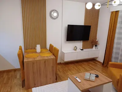 a living room with a table and a flat screen tv at Larso Lux, free swimming pools & parking in Vrnjačka Banja