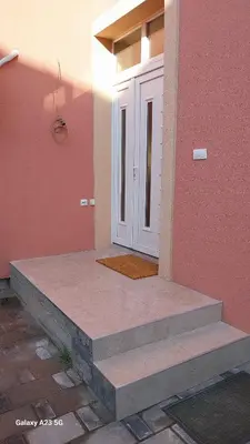 a front door of a pink house with stairs at Apartman Mina in Pirot