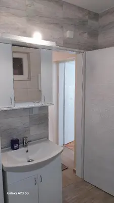 a white bathroom with a sink and a mirror at Apartman Mina in Pirot