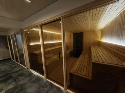 a small sauna with a wooden floor and glass walls at Apartman Aska - Residence Hill in Kopaonik