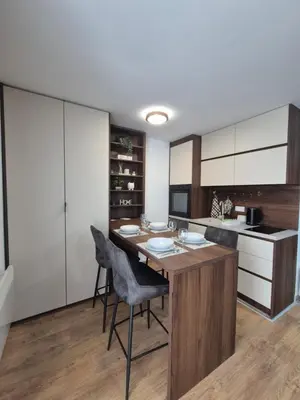 a kitchen with a island with chairs and a table at Avalon apartments in Kopaonik