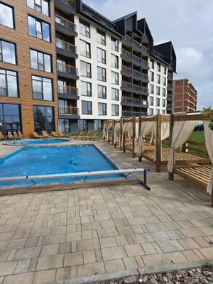 a swimming pool with chairs and a large building at Epic Apartments in Kopaonik