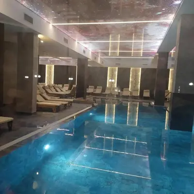 a large pool with blue water in a hotel lobby at Epic Apartments in Kopaonik